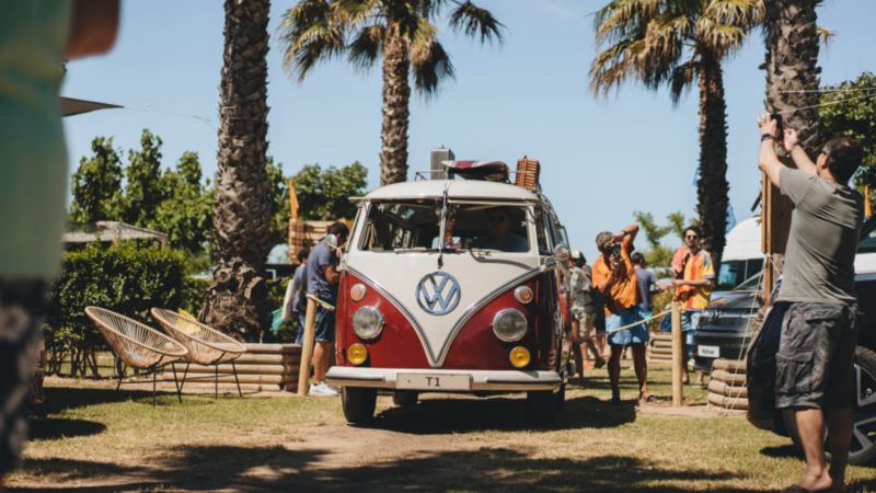 Una furgo clásica de Volkswagen en un camping rodeada de gente