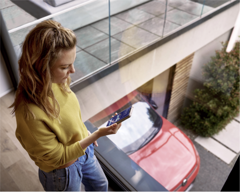 Woman using smartphone to perform over-the-air vehicle software updates.