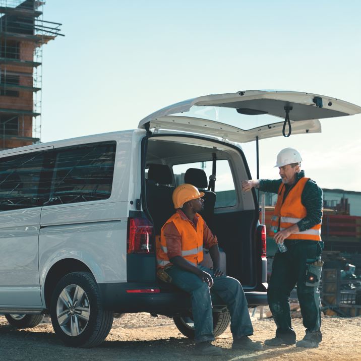 Deux ouvriers de chantier discutent à l'arrière de leur véhicule Volkswagen Utilitaire