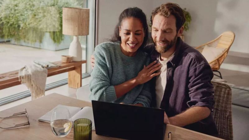 Happy couple selecting their new Volkswagen model online using the find your Volkswagen tool on their laptop