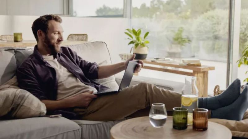 VW customer comparing service plans whilst relaxing on the couch with his feet up