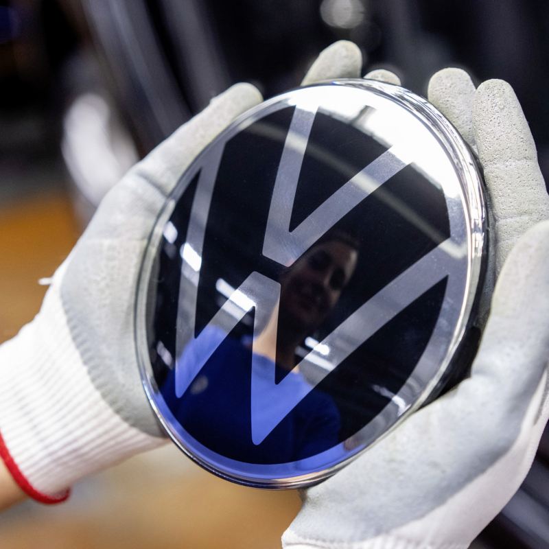 VW Emblem in Händen eines Mitarbeiters