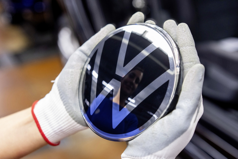 A production employee holds the VW logo in both hands