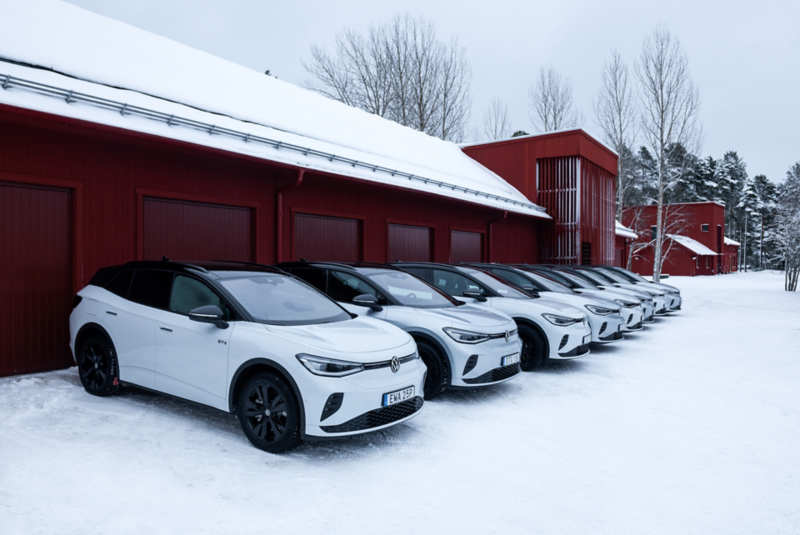 Volkswagen ID.-bilar parkerade på rad utanför ett rött garage. Snötäckt landskap