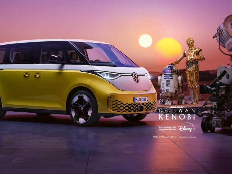 Ένα λευκό-κίτρινο VW ID. Buzz στέκεται σε ημιπροφίλ σε έναν άγνωστο πλανήτη του σύμπαντος Star Wars με δύο ήλιους και φορτίζει με ρεύμα. 2 droids βρίσκονται δίπλα του.