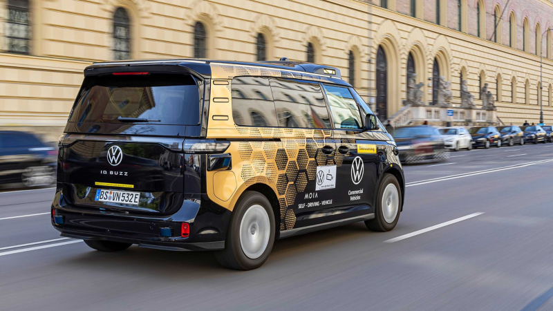 Exterior photo showing an autonomous VW van driving along a city street. 