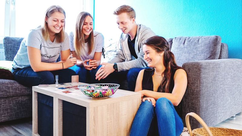 Junge Menschen sitzen gemeinsam in einer Wohnung um einen Tisch