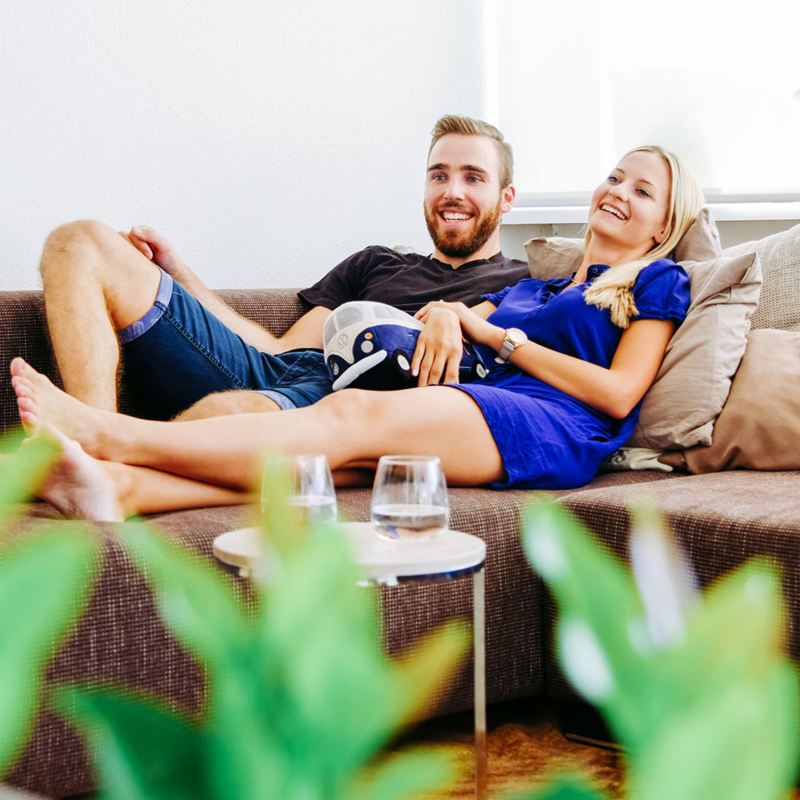 Mann und Frau liegen auf einem Sofa und schauen TV