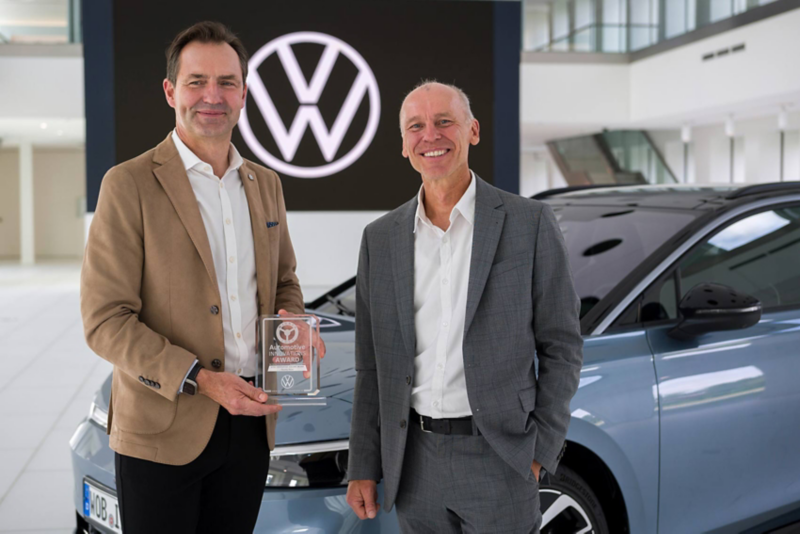 Teaserbild Thomas Schäfer und Prof. Dr. Stefan Bratzel vom CAM bei der Preisübergabe freudestrahlend vor einem Auto