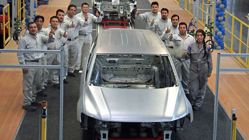 Historia de Volkswagen México - Empleados dentro de planta VW rodeando automóvil en producción