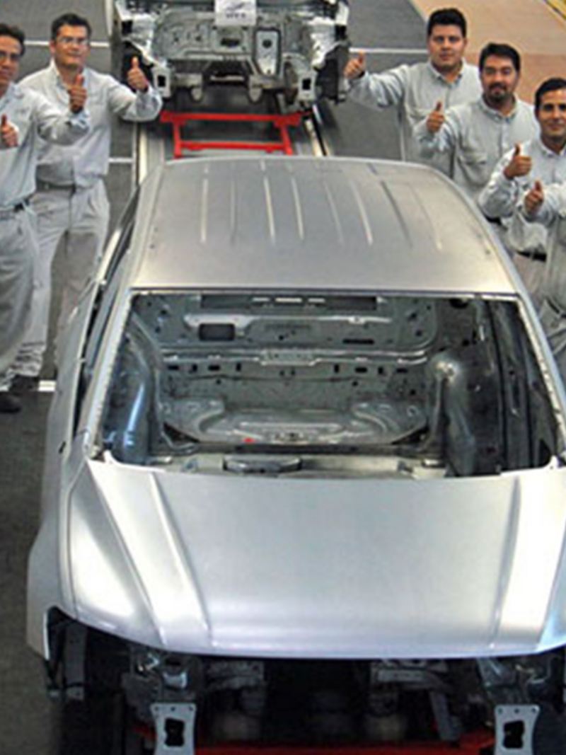 Historia de Volkswagen México - Empleados dentro de planta VW rodeando automóvil en producción