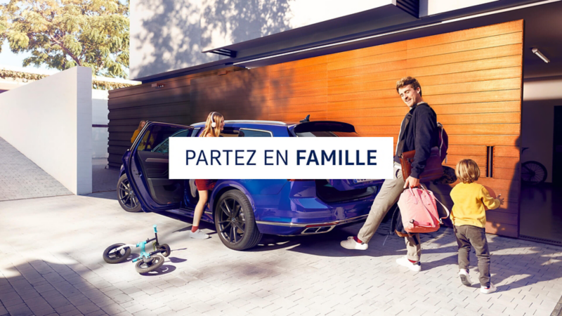 Une famille s'installe dans une passat sw bleue et range les bagages - Partez en famille