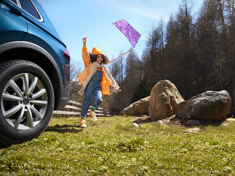 Una bambina gioca a fianco di una vettura Volkswagen 
