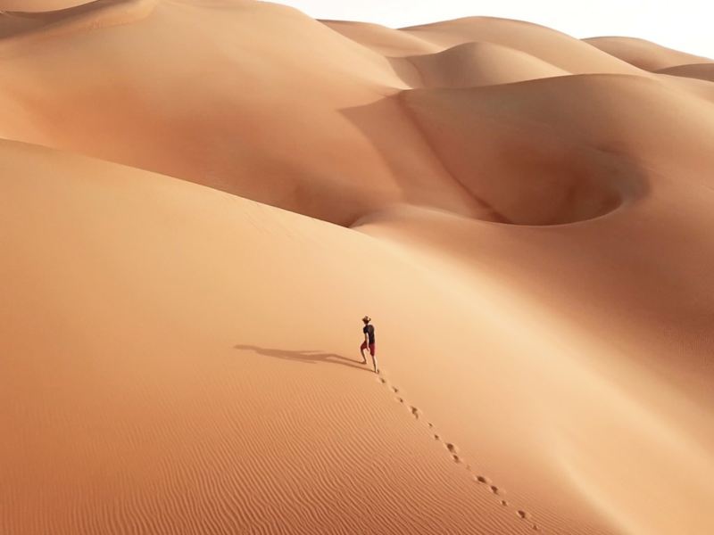  Un uomo percorre una duna di sabbia in salita