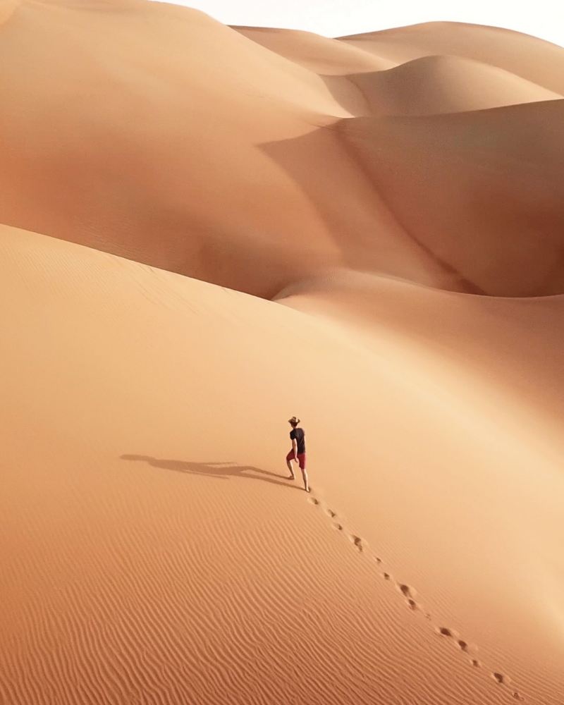  Un uomo percorre una duna di sabbia in salita