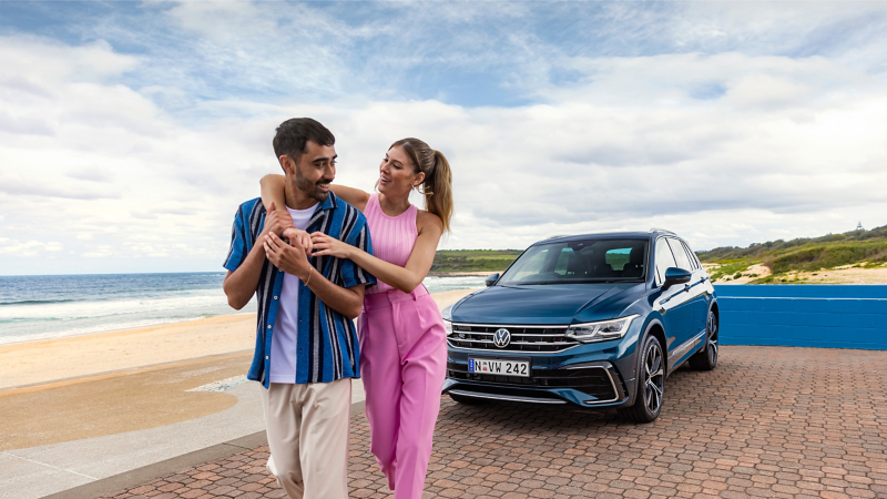 Couple stood in front of blue VW car