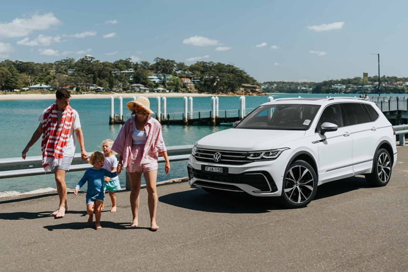 Family around Volkswagen Tiguan Allspace which is parked on the rooftop.