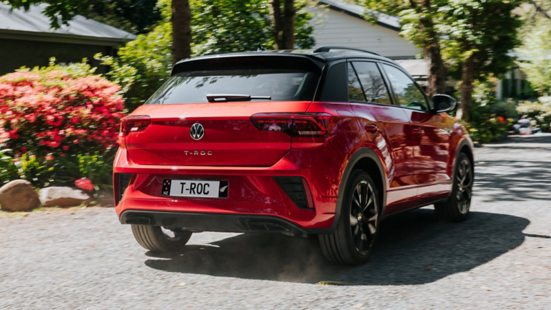 VW T-Roc R-Line in grey drives dynamically over intersection, visible from the side