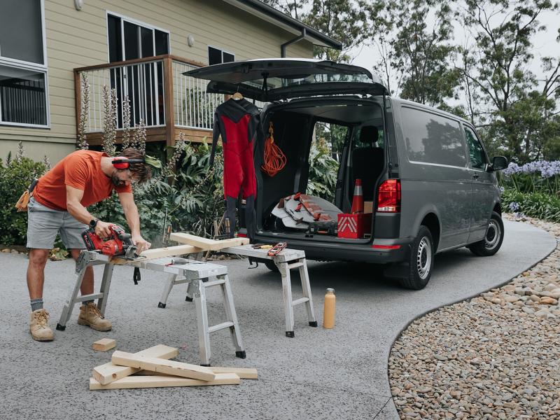Volkswagen Transporter with man cutting wood with equipment loaded on and off the Transporter car