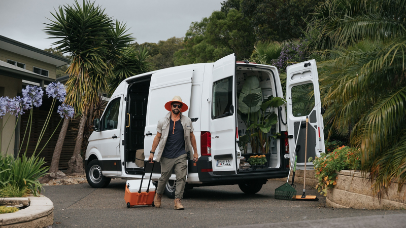 Man walking past Volkswagen crafter van with his luggage.