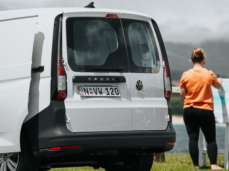 Volkswagen Caddy with woman paiting outside