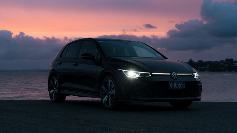 Golf GTE at sunset with the lights on
