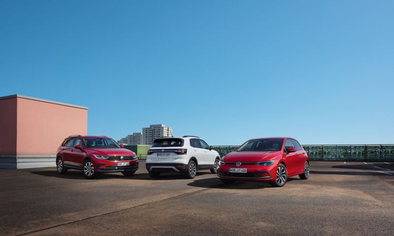 3 VW μοντέλα: ένα κόκκινο Tiguan, ένα λευκό T-Cross και ένα κόκκινο Golf. Σε έναν χώρο στάθμευσης.
