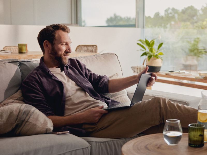 Mann sitzt zu Hause und schaut auf ein Tablet