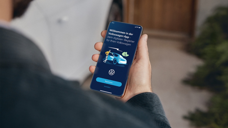 Person schaut auf ein Mobiltelefon und bedient die Volkswagen App