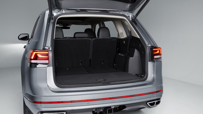 Rear view of a silver Volkswagen Atlas with the power tailgate open, showing spacious cargo area with upright third-row seats.