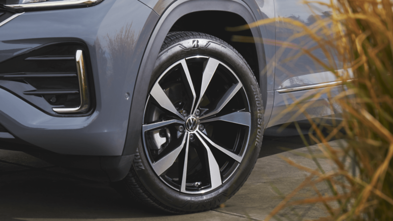 Close-up of the front wheel and tire of a grey Volkswagen Atlas Cross Sport, featuring machined alloy wheels with a modern, black and silver design. 