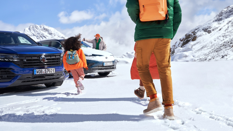 Familie läuft im Schnee auf ihren Volkswagen zu