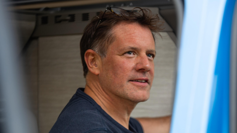 Close-up of chef Matt Tebbutt smiling while seated inside the camper van.