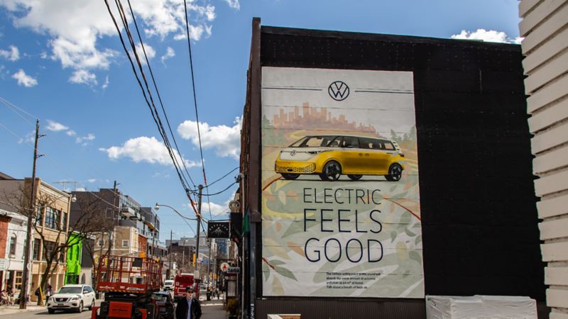 Une grande murale sur lequel il est écrit Electric Feels Good et mettant en vedette un ID.Buzz jaune