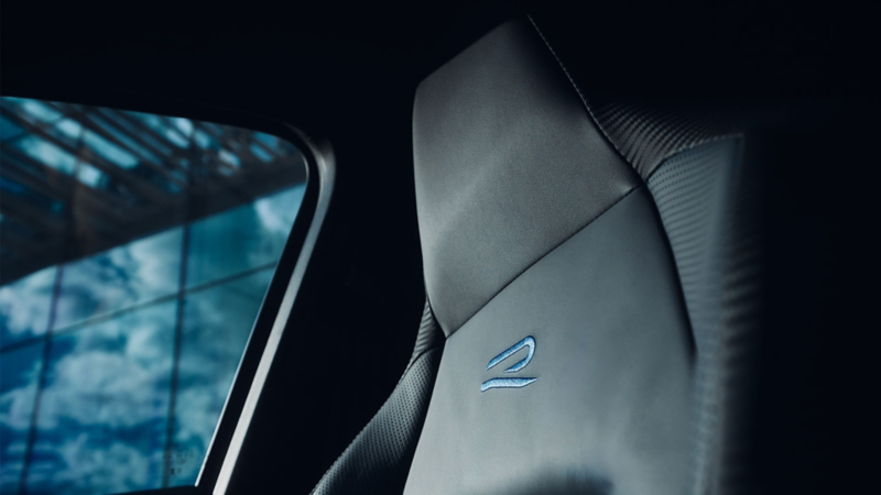 Un homme est assis au volant et utilise la console centrale. Une personne est assise à l'extérieur de la voiture, sur le capot.