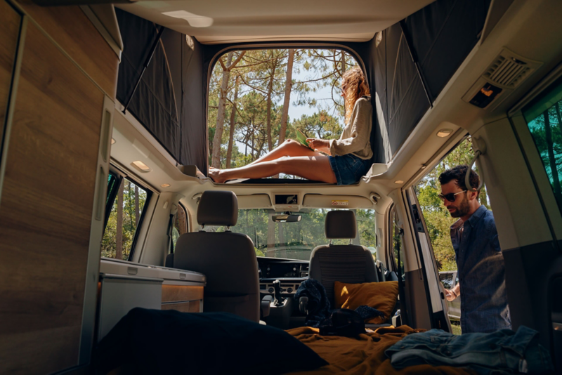 femme et homme heureux et souriant avec vue intérieure dans le VW California 6.1