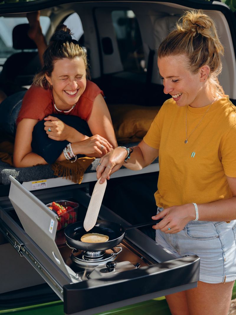VW California vue cuisine avec 2 femmes qui utilisent les plaques