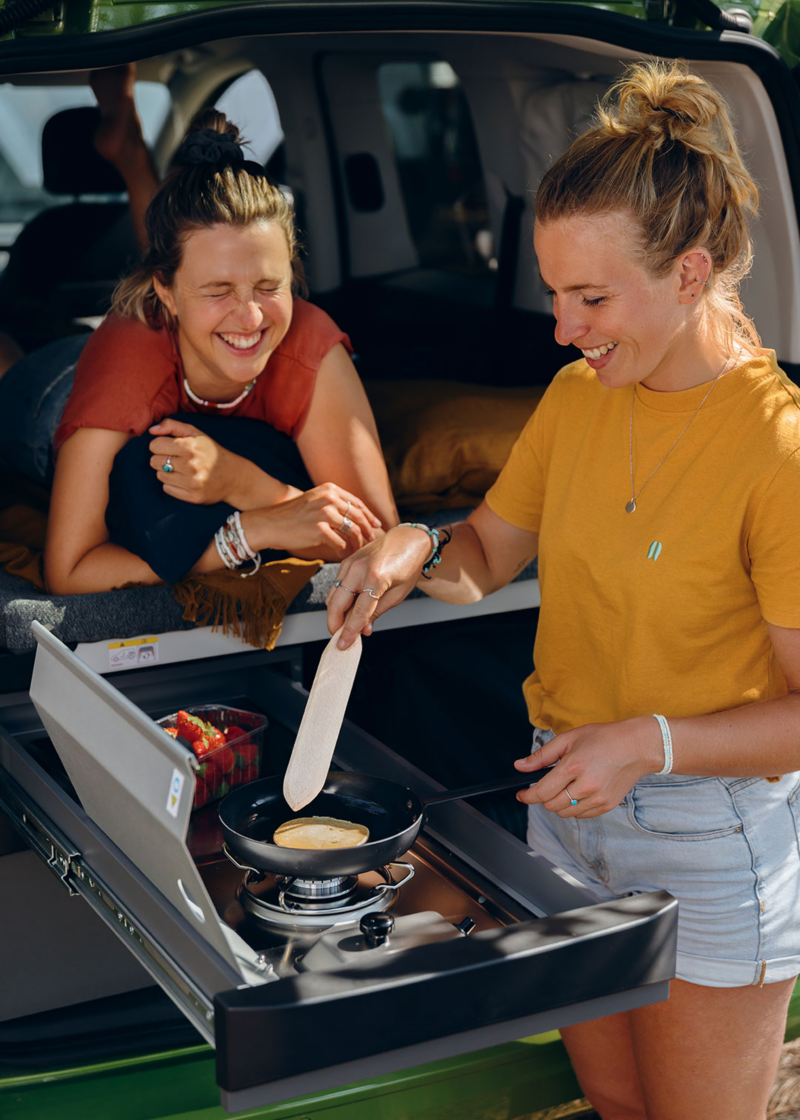 VW California vue cuisine avec 2 femmes qui utilisent les plaques