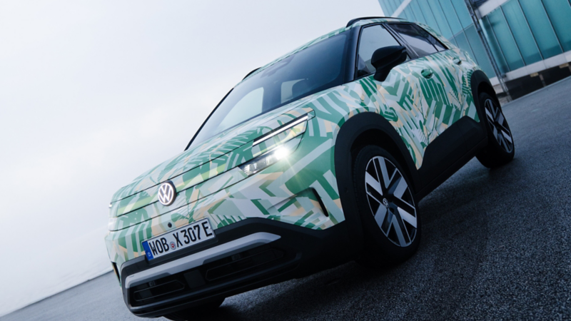 Ein VW ID. Cross mit Konzeptbeklebung in 3/4-Vorderansicht vor modernem Hochhaus.