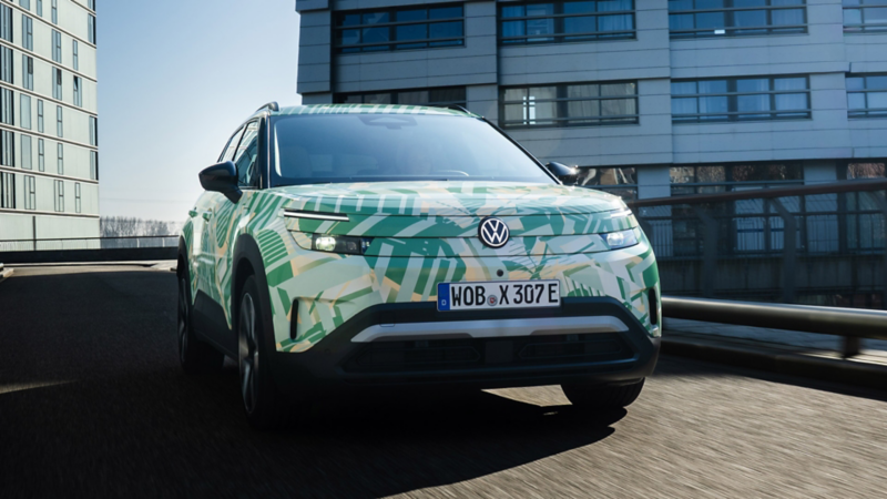 Ein VW ID. Cross mit Konzeptbeklebung auf einem urbanen Parkdeck vor modernem Hochhaus.