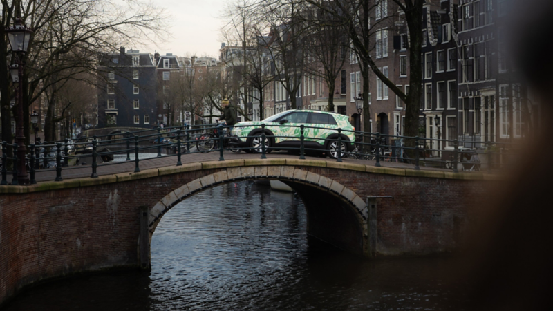 Ein VW ID. Cross mit Konzeptbeklebnung fährt auf einer Backsteinbrücke.