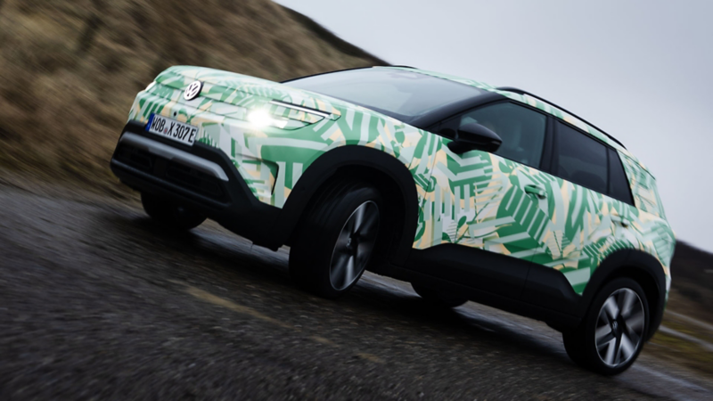 Ein VW ID. Cross mit Konzeptbeklebung fährt dynamisch durch eine Berglandschaft.