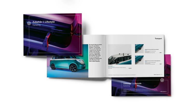  Une composition d'Une brochure ouverte de Volkswagen "Zubehör & Lifestyle" présente des accessoires et un aperçu d'un véhicule, sur un fond sombre.sur une surface en bois, comprenant un carnet noir avec le logo Volkswagen, des partitions de musique, des boutons de manchette, une clé de voiture et un stylo.