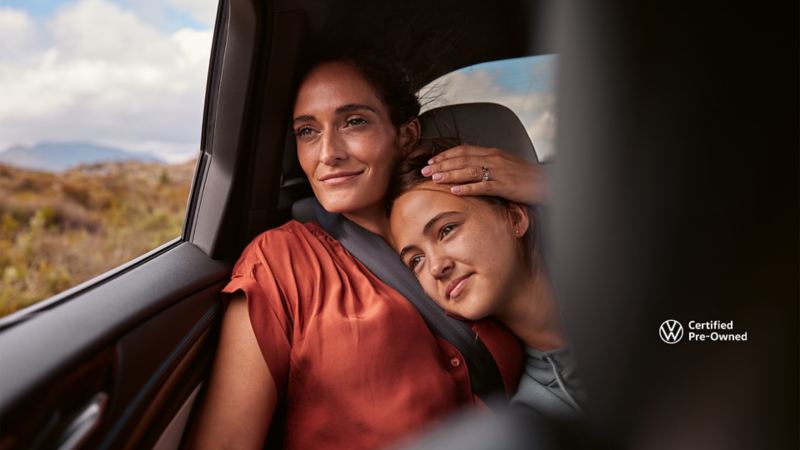 Two people sitting closely in the back of a vehicle