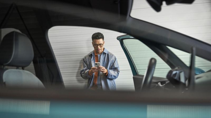 A view of a man on his phone from the inside of a vehicle