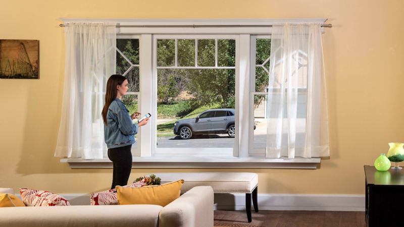Woman standing in front of window using the remote access feature on the Car-Net® app