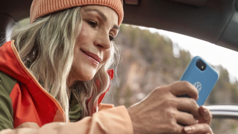 A woman is holding a phone with a Volkswagen case cover