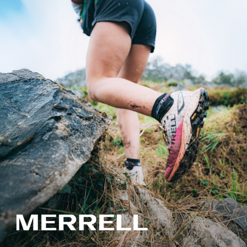 Una persona corriendo por la montaña con unas zapatillas Merrell
