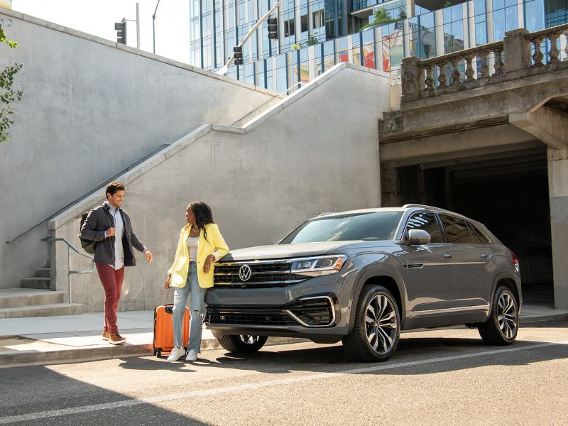 We see a man and woman talking in front of a grey Cross Sport parked on the street.