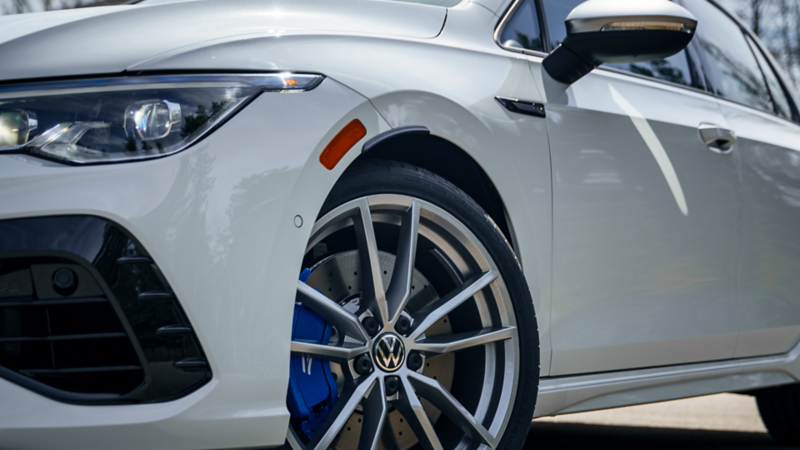 Une roue avant d'une Volkswagen Golf 2024 blanche avec des plaquettes de frein bleues.